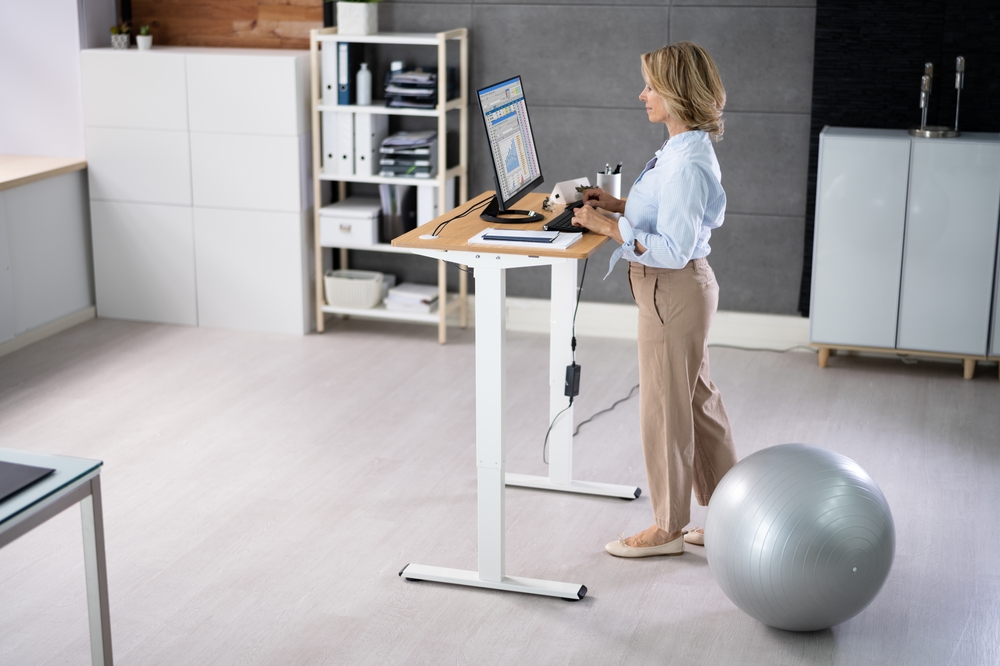 Woman,Using,Adjustable,Height,Standing,Desk,In,Office,For,Good