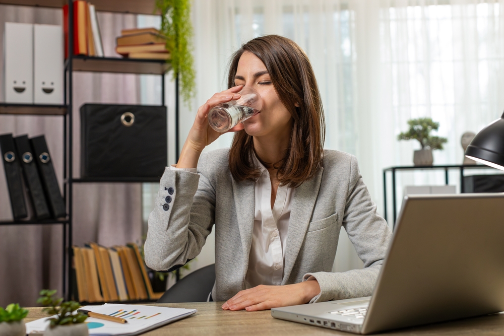 Focused,Young,Businesswoman,Girl,Sitting,At,Workplace,Desk,Drinking,Water